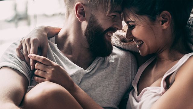 homme souriant avec une barbe dans les bras de sa femme souriante