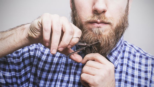 homme qui taille sa barbe avec un ciseaux